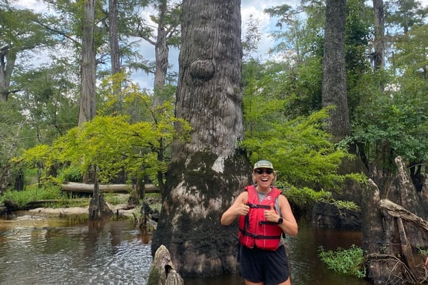 Sam Burton is smiling in front of a tree in the Black River.